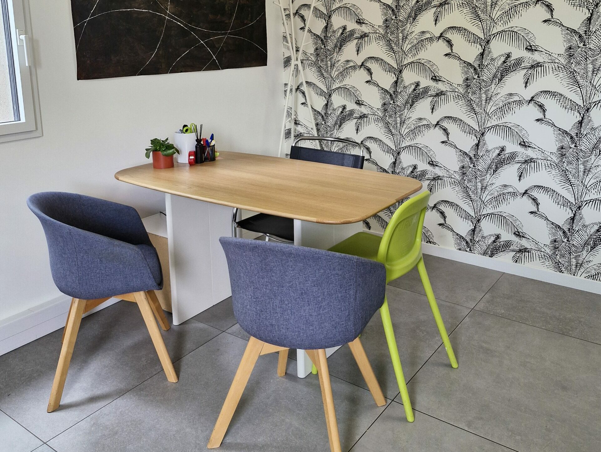 Bureau de consultation lumineux avec une table en bois, deux fauteuils, une chaise haute pour enfant dans une ambiance moderne et accueillante.